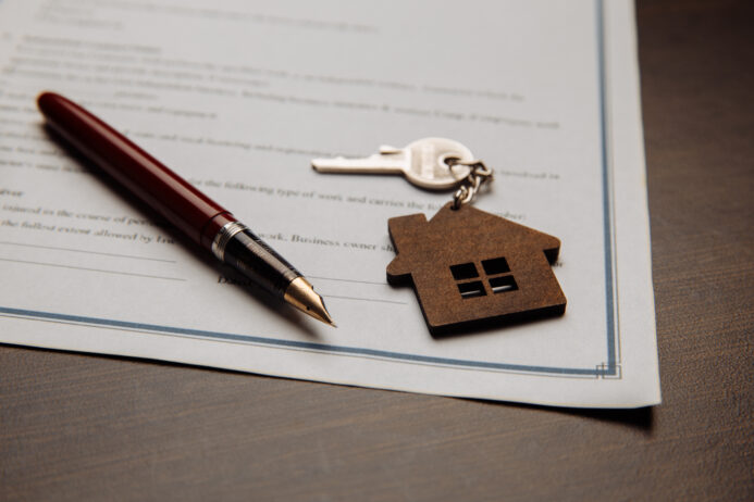 House keys and money on a signed contract of house sale. Focus on keys.