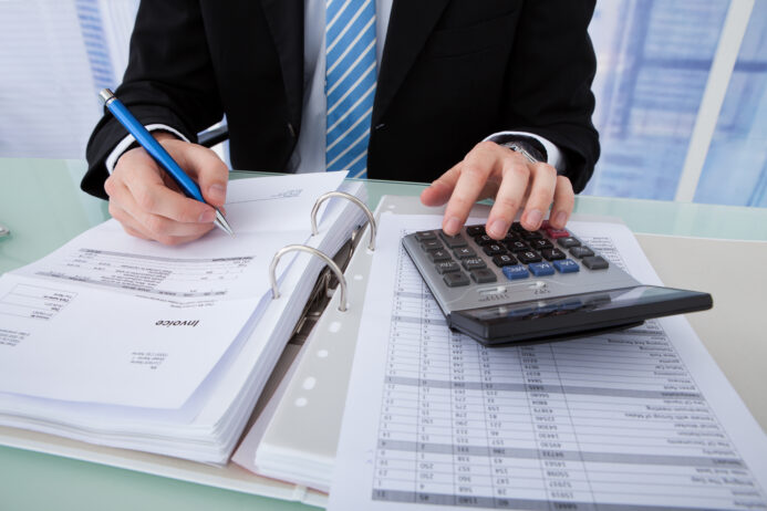 Midsection of young businessman calculating invoice at office desk